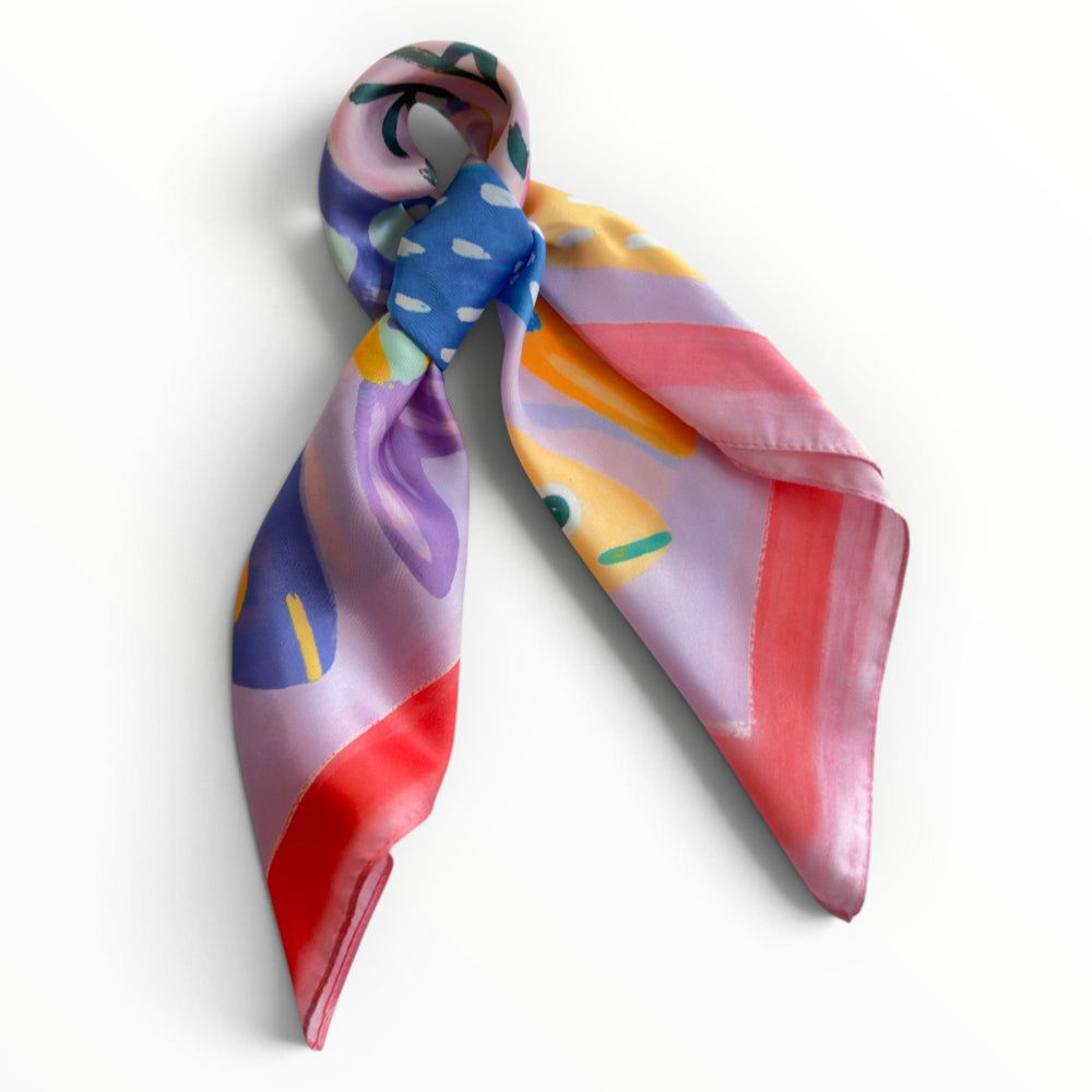 Pink Sardine Chic silky square scarf tied in a loose knot, showing its colourful fish print and soft pink and blue tones.